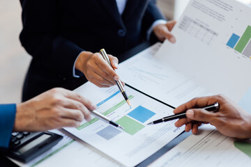 Close up view of business people discussing the charts and graphs showing the results of their successful teamwork.