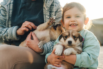 Beautiful woman with little baby girl cuddling a small puppy. Family, pet, domestic animal and people concept. Young mother with girl and dog. The concept of