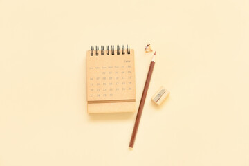 Flip paper calendar for June with pencil and sharpener on beige background