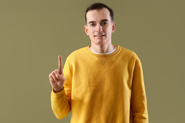 Young man showing one finger on green background