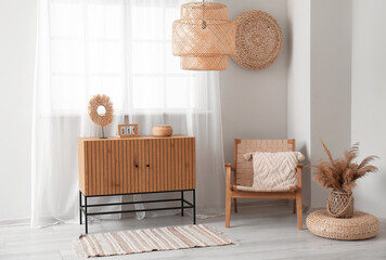 Interior of light living room with wooden commode and armchair