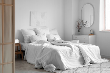 Interior of light bedroom with mirror and commode