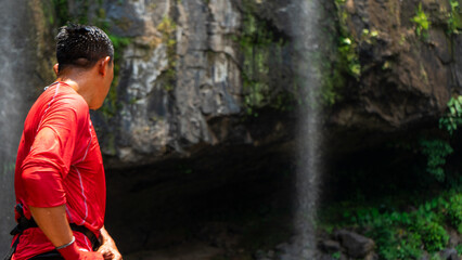 Fototapeta na wymiar Unrecognizable man prepared to climb the rocky area of a waterfall in the mountainous area of Matagalpa, Nicaragua