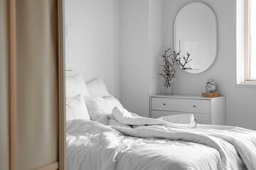 Interior of light bedroom with mirror and commode