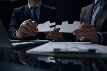 Business concept: Hands of two businessmen holding puzzle pieces