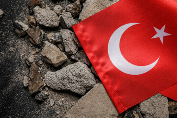 Turkish flag with stone debris on dark background. Turkey earthquake concept