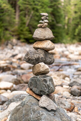 Fototapeta na wymiar Rocks are shown stacked in a river bed against a backdrop of fir trees in Washington state.