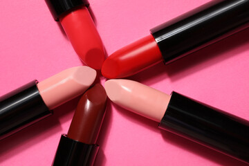 Different lipsticks on pink background, closeup