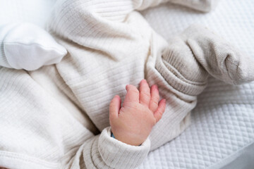 hands of a newborn dressed in light-colored clothes