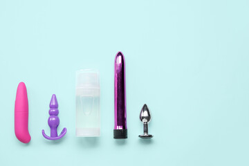 Bottle of lubricant with vibrators and anal plugs on blue background