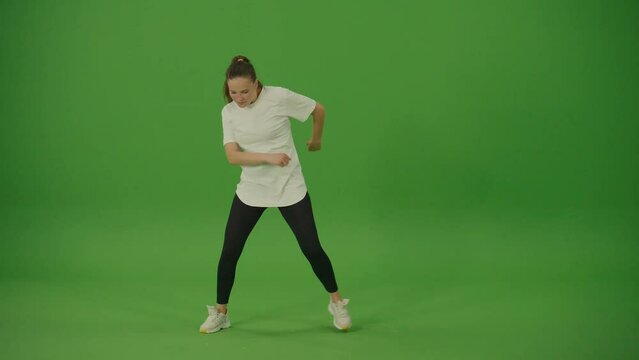 Professional Female Dancer Performing a Dance on a Green Screen. Chroma Key. Green Screen. Modern Lifestyle, Happiness Concept. Breakdancing, Hip-Hop Dancing, Street Dancing.