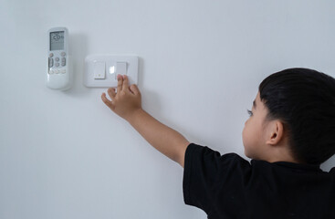 Back view at little careless child boy exploring house playing turning light switches