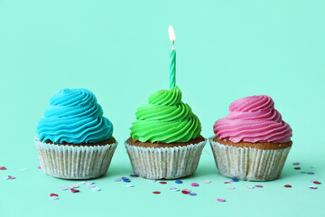Tasty cupcakes with birthday candle on blue background