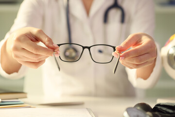 Woman doctor giving pair of black glasses to patient