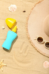 Fototapeta na wymiar Creative composition with sunscreen cream, summer hat and sunglasses on sand