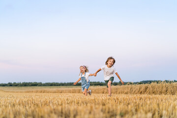 Fototapeta na wymiar Happy and free people, children run through the beveled field of wheat