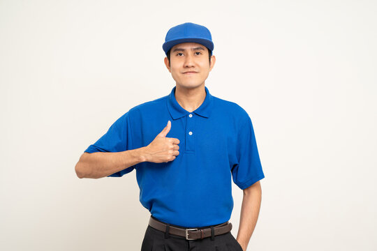 Happy asian man in blue uniform standing on isolated white background. Smiling male delivery service worker. Delivery courier and shipping service.