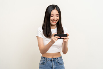 Fototapeta premium Excited Beautiful young asian women play mobile game and standing on isolated white background. Playing game on smartphone winning victory moment. Very enjoy and fun relax time