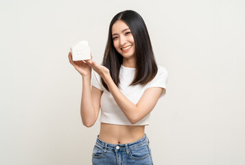 Young cute asian woman holding house mock up standing on isolated white background. Real estate and...