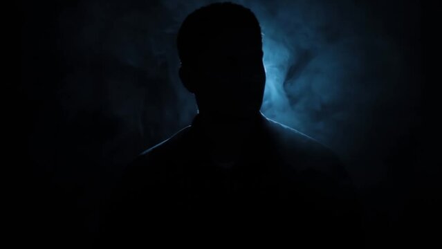 Close-up creative shot of a man sitting on a chair with rim light creating a silhouette, Hd footage.
