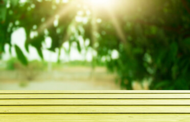 Fototapeta premium Wooden table top with natural green blurred background or various leaves, fresh bright sunlight, product empty concept.