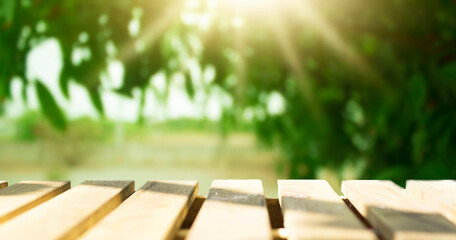 Wooden table top with natural green blurred background or various leaves, fresh bright sunlight, product empty concept.