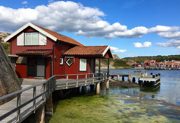 Fototapeta na wymiar traditional red cabin on a pontoon in front of the sea under blus sky in sweden -Fjallbacka
