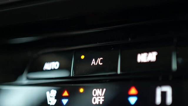Pressing the AC Button on a Car Climate Control Panel Closeup