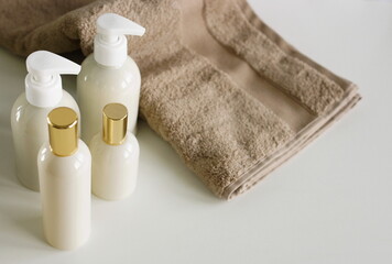 Natural cosmetic skincare bottles mockup and towel on white background with copy space. Product presentation. Beauty and body care products. Neutral beige colors. 
