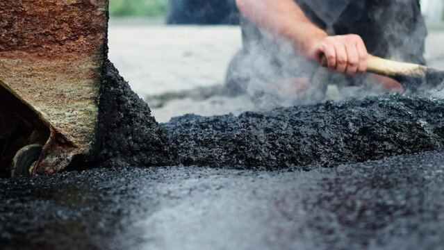 Road construction workers manually Spread and adjust hot tar or asphalt on the ground at the pavement building site
