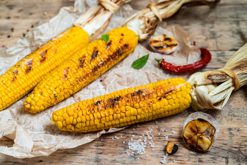 grilled corn with tied cobs on wooden boards with butter and spices