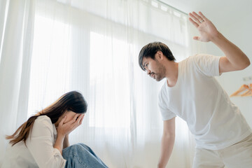 Obraz premium Domestic Violence, Asian Husband Threatening Wife, Scared Mother Embracing is her While Sitting Together On bed.