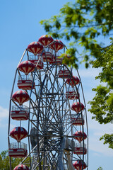 Colorful ferris wheel of the amusement park in the blue sky background.