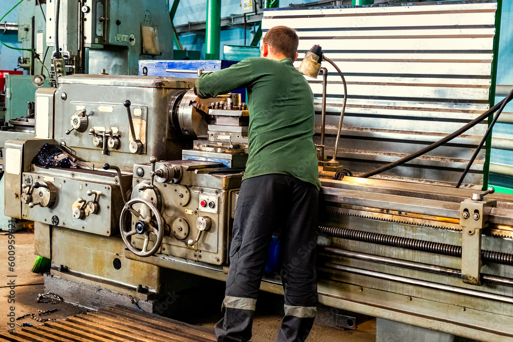 Poster a working man works on a lathe. processing of metal blanks in a workshop in a modern factory. indust