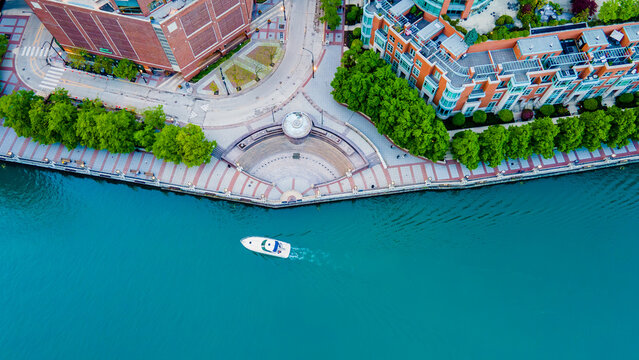 aerial drone view of the Chicago river with a boat sailing along the stream .  the water front is a great tourist destination for sight seeing and travel.  the blue water is beautiful and serene 