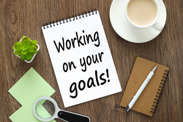 text WORKING ON YOUR GOALS on white note paper near coffee cup