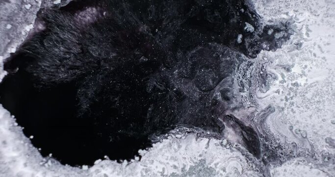 Black and white shiny paint abstract background, close up. Dark liquid abyss in white hole. Black paint spread to frosty white. Black fluid flowing, spreading. Sparkling paints. 4k moving footage
