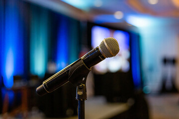 microphone in front of a blue stage background turquoise green curtains singer speech public...