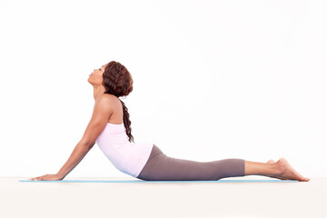 Yoga, cobra back stretch and black woman relax in studio on a fitness and workout mat for training. Isolated, white background and calm African female person lying on the ground with body stretching - obrazy, fototapety, plakaty