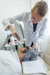 dermatologist wearing a medical mask and rubber gloves applies a mask to a client's face.