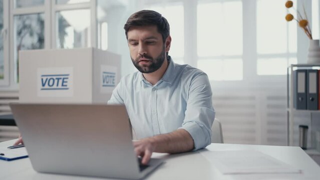Busy poll worker typing information on laptop in office, election campaign