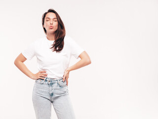 Fototapeta premium Young beautiful woman. Trendy carefree model in casual summer white T-shirt and blue jeans. Positive female isolated on white in studio. Cheerful and happy. Copy space, mockup. Makes duck face