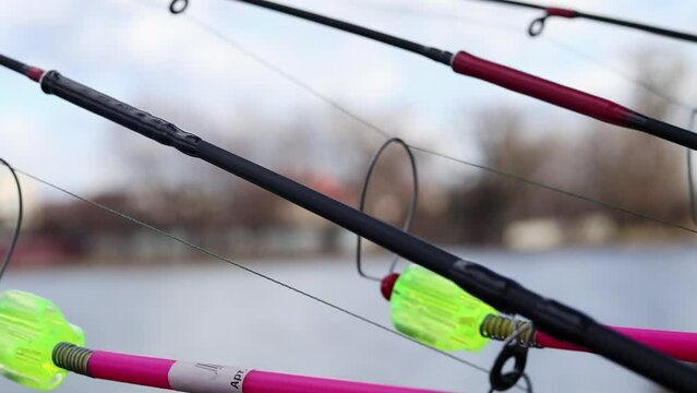 The bite alarm hangs on a fishing rod against the background of water. Fishing rod while fishing on the lake, river. Fishing tackle. Carp rod on a stand with a bite alarm on the line.