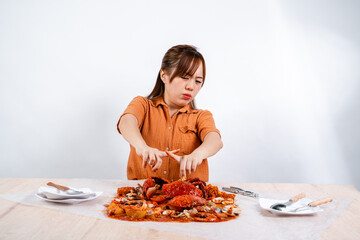 Young Asian woman say no to eating seafood, crab with padang sauce (Indonesian : Kepiting Saus Padang) isolated on white background