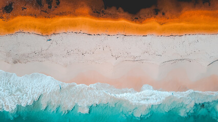 Aerial view of where the river meets the sea. Vibrant orange and dark river meet turquoise sea waves on beach in Western Australian town called Guilderton. © Matt