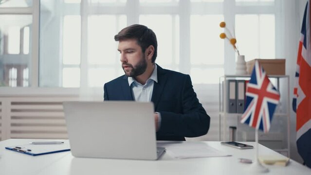 British embassy employee processing visa document, checking database on laptop