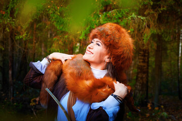 Girl in a leather jacket, a big red fox fur hat and with the skin of a fox killed on the hunt in...