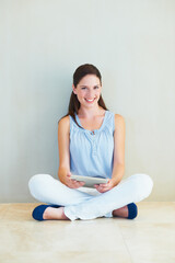 Portrait, tablet and a woman sitting legs crossed on the floor of her home browsing social media with a smile. Happy, technology and app with a young female person using the internet against a wall