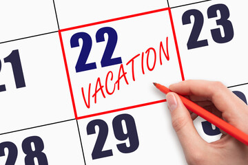 22nd day of the month. Hand writing text VACATION on calendar date.