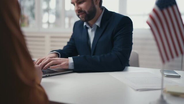 USA consular service employee checking computer data, issuing visa to applicant